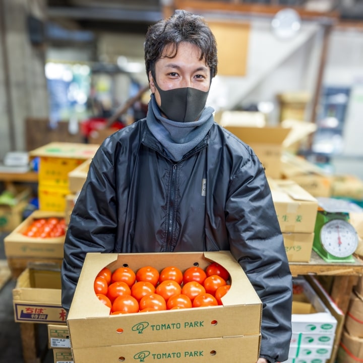 トマトの箱を持つ男性従業員